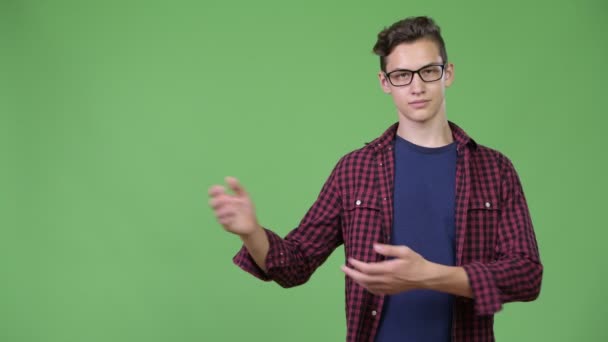 Young handsome teenage nerd boy showing something — Stock Video