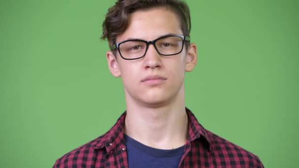 Young handsome teenage nerd boy with finger on lips — Stock Video