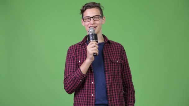 Young handsome teenage nerd boy using microphone — Stock Video