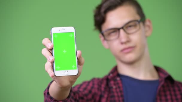 Young handsome teenage nerd boy showing phone — Stock Video