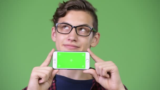 Jovem bonito adolescente nerd menino mostrando telefone — Vídeo de Stock