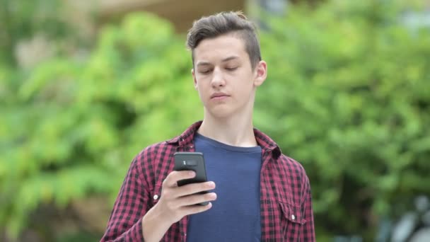 Ευτυχισμένος εφηβικό αγόρι χρησιμοποιώντας τηλέφωνο σε εξωτερικούς χώρους — Αρχείο Βίντεο