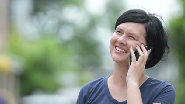 Šťastná krásná žena mluví po telefonu venku — Stock video