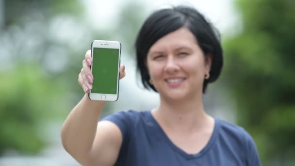Mulher bonita feliz mostrando telefone ao ar livre — Vídeo de Stock