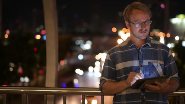 Hombre de negocios guapo usando tableta digital en la noche — Vídeo de stock