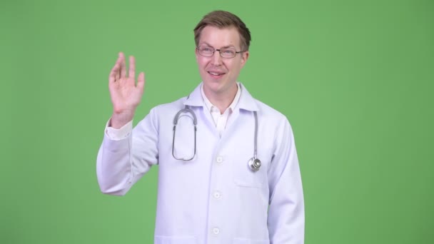 Retrato del joven doctor sonriendo y saludando con la mano — Vídeo de stock