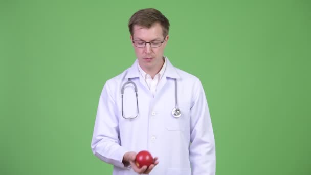 Портрет молодого человека, играющего с красным яблоком — стоковое видео