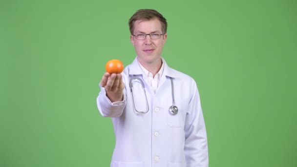 Portrait de jeune homme docteur tenant des fruits orange — Video