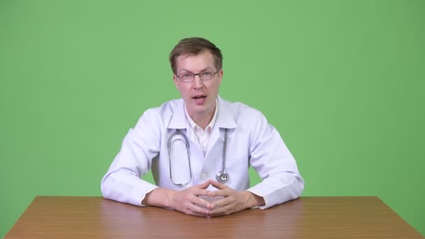 Joven hombre confiado Doctor sentado y hablando mientras sonríe — Vídeos de Stock