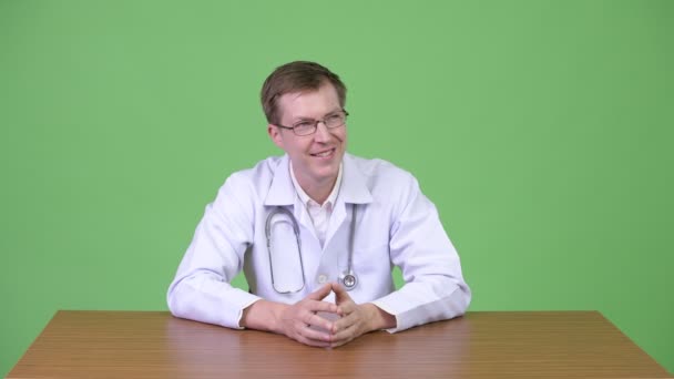 Retrato de un joven feliz Doctor sentado y pensando — Vídeos de Stock