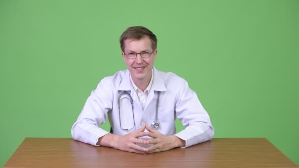 年轻男子医生的肖像坐在微笑, 并给拇指 — 图库视频影像