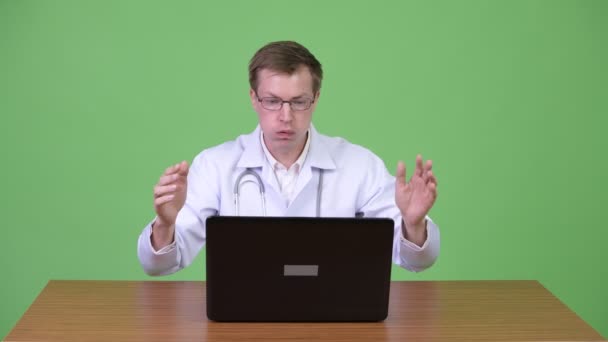 Médico surpreso sentado e usando o computador portátil enquanto recebendo más notícias — Vídeo de Stock