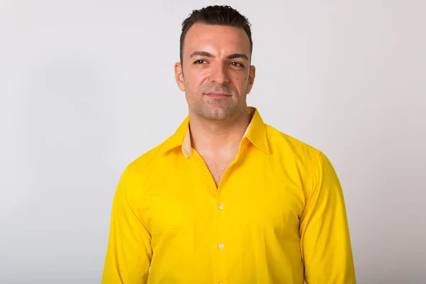 Ritratto di uomo che indossa una camicia gialla sullo sfondo bianco — Foto Stock
