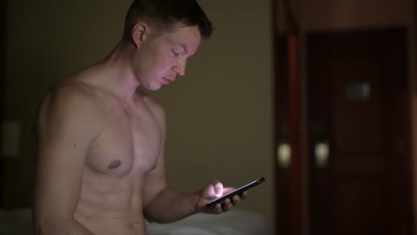 Hemdloser Mann benutzte Handy nachts im Hotelbett — Stockvideo