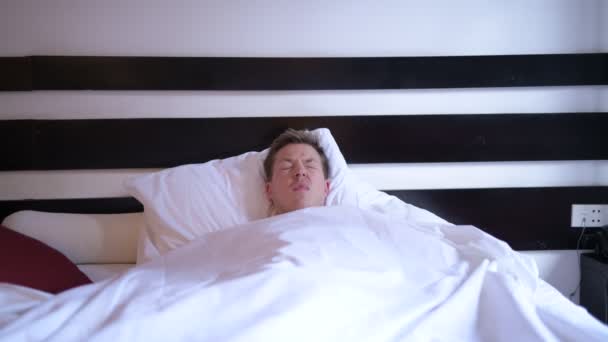 Gestresster Mann im Bett hat Wecker zu spät — Stockvideo