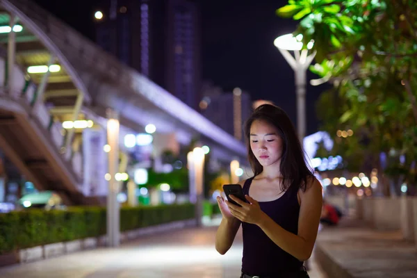 Vacker asiatisk kvinna Utomhus nattetid med hjälp av mobiltelefon — Stockfoto