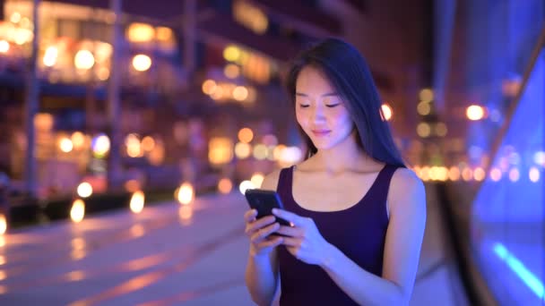 Mulher asiática bonita ao ar livre à noite usando telefone móvel — Vídeo de Stock