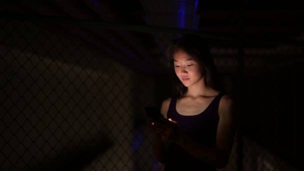 Mulher asiática bonita ao ar livre à noite usando telefone móvel — Vídeo de Stock