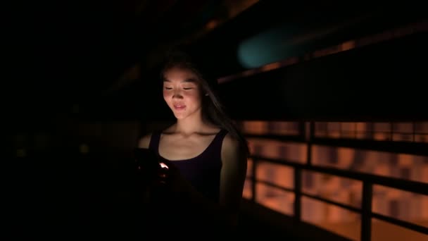 Hermosa mujer asiática al aire libre en la noche usando el teléfono móvil — Vídeos de Stock