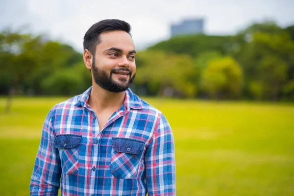 Feliz jovem bonito indiana homem no parque pensando — Fotografia de Stock