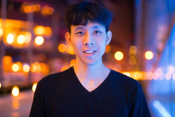 Retrato de homem asiático sorrindo ao ar livre à noite — Fotografia de Stock