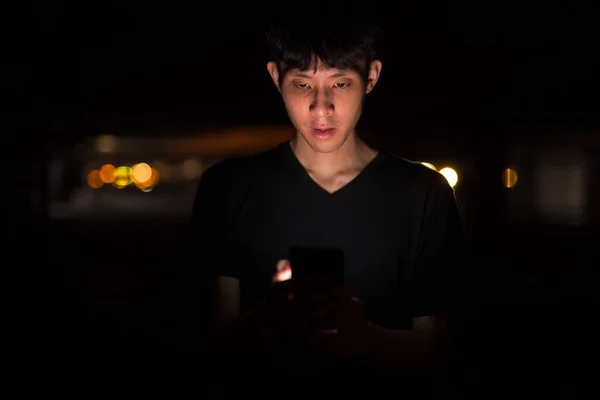 Портрет азіатського чоловіка на відкритому повітрі вночі на парковці за допомогою мобільного телефону — стокове фото