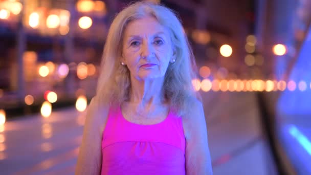 Portret van Senior vrouw die lacht buitenshuis in de nacht — Stockvideo