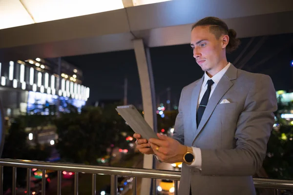 Молодой красивый бизнесмен на открытом воздухе ночью с помощью цифрового планшета — стоковое фото