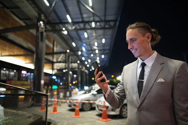 Молодой привлекательный бизнесмен на открытом воздухе ночью с помощью мобильного телефона — стоковое фото