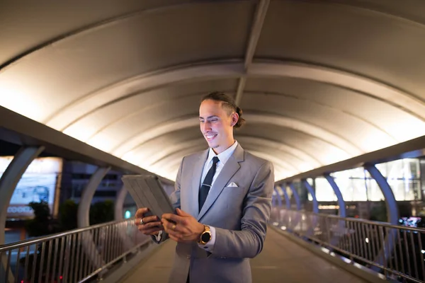 Бизнесмен на открытом воздухе ночью с помощью цифрового планшета — стоковое фото