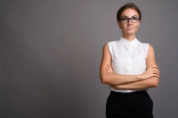 Young beautiful businesswoman against gray background — Stock Photo, Image