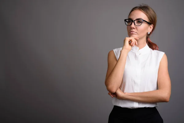 Ung vacker affärskvinna mot grå bakgrund — Stockfoto