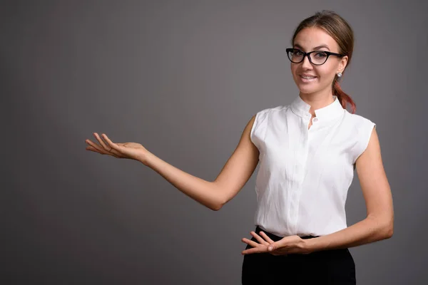 Junge schöne Geschäftsfrau vor grauem Hintergrund — Stockfoto