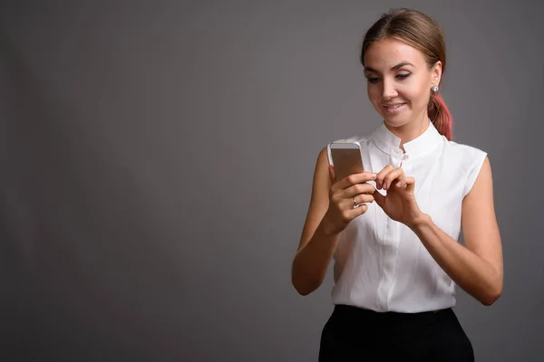 Young beautiful businesswoman against gray background — Stock Photo, Image