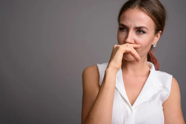 Ung vacker affärskvinna mot grå bakgrund — Stockfoto