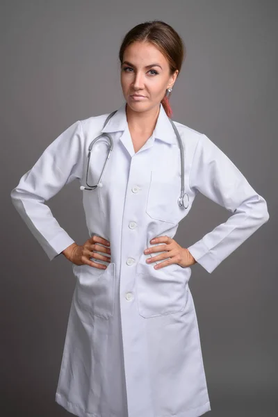 Jovem mulher bonita médico contra fundo cinza — Fotografia de Stock