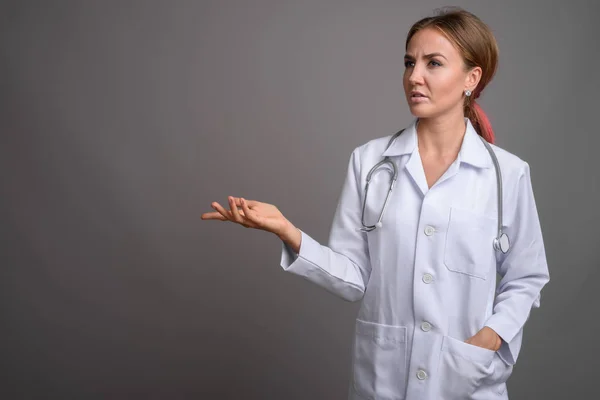 Junge schöne Ärztin vor grauem Hintergrund — Stockfoto