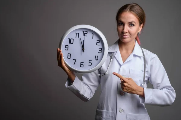 Joven hermosa mujer médico contra fondo gris — Foto de Stock