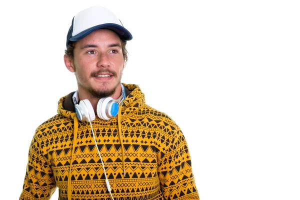 Pensativo jovem feliz homem sorrindo enquanto vestindo boné e headpho — Fotografia de Stock