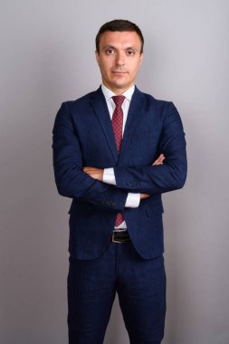Gri arka planda takım elbise giyen bir işadamı