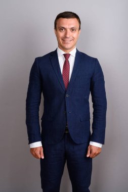 Gri arka planda takım elbise giyen bir işadamı