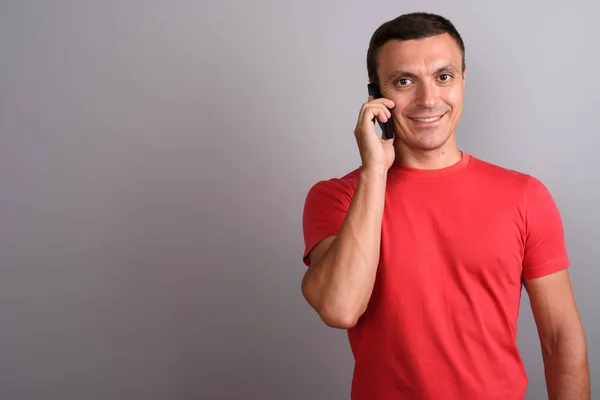 Mannen bär röd skjorta medan du använder mobiltelefon mot grå rygg — Stockfoto