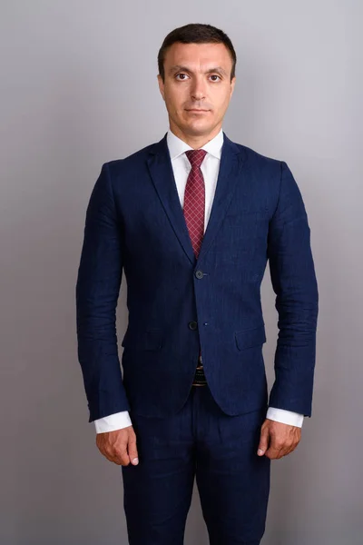 Obchodník nosí oblek na šedém pozadí — Stock fotografie