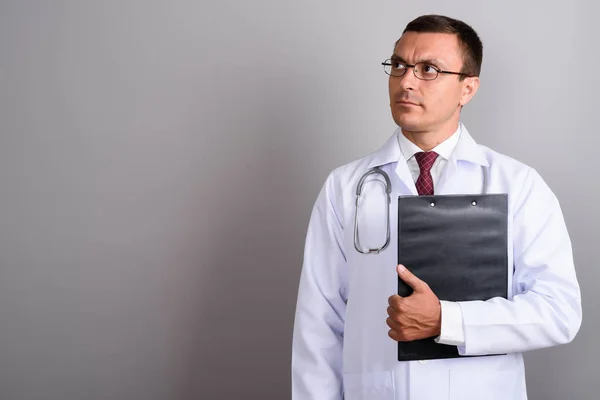 Hombre doctor usando anteojos contra fondo gris —  Fotos de Stock