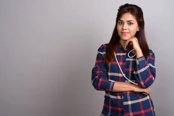 Young beautiful Indian woman wearing checked shirt against gray
