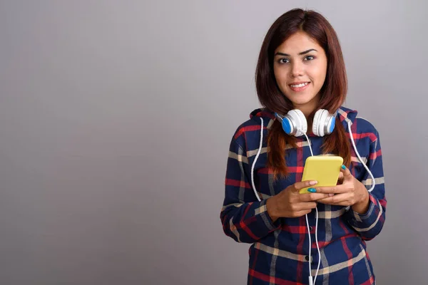 Молодая красивая индийская женщина в наушниках и с помощью мобильного телефона — стоковое фото