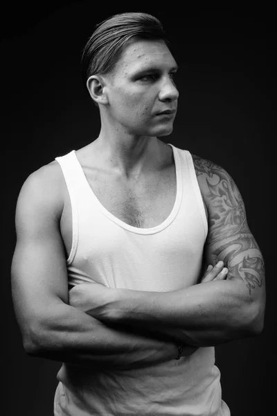 Homem muscular vestindo top tanque branco contra fundo preto em — Fotografia de Stock