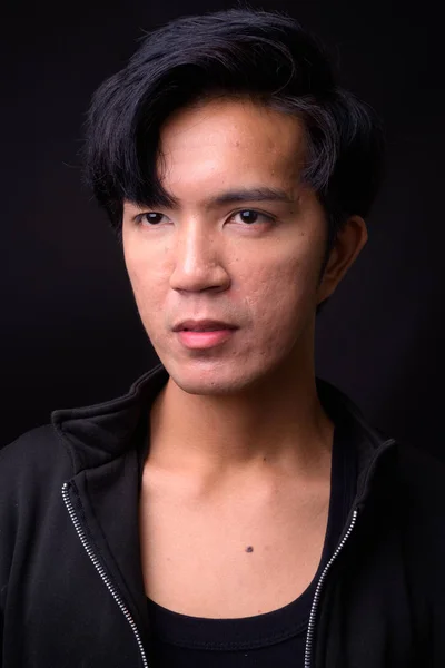 Jonge knappe Aziatische man tegen zwarte achtergrond — Stockfoto