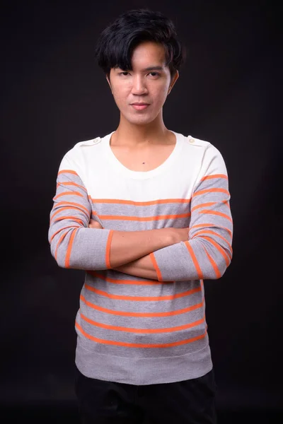 Young handsome Asian man against black background