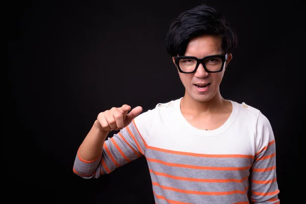 Young handsome Asian man against black background — Stock Photo, Image